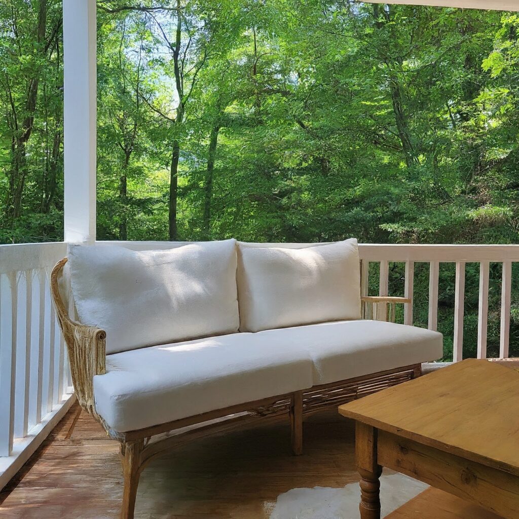 white couch on wrap around porch in summer with wooden table featured 