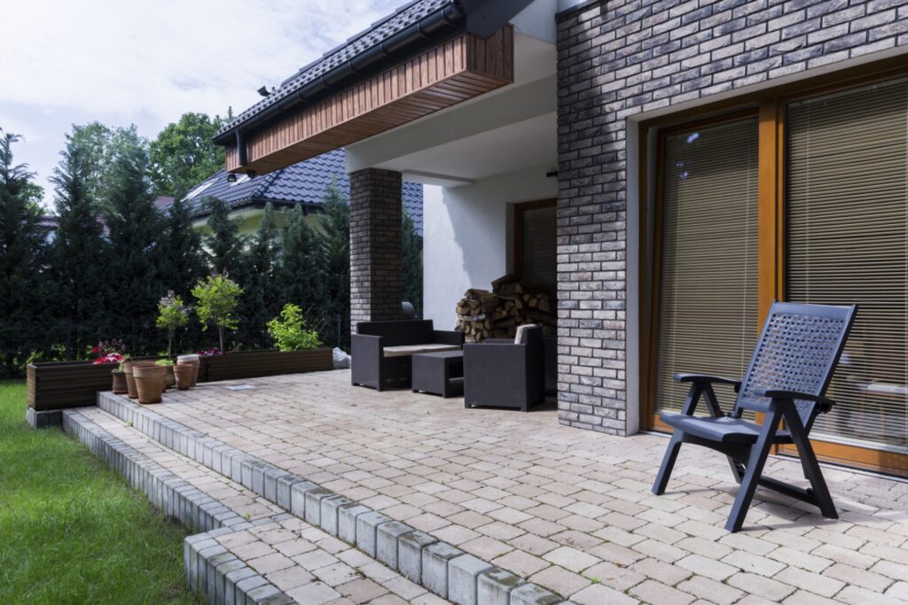 Finished paver patio with a raised paver step and garden furniture behind a Charlotte-area home